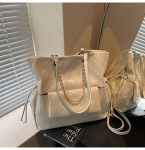 Macro detail of quilted cream tote bag showing chain strap and front flap pocket