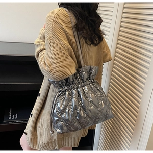 Detail of silver metallic quilted bucket bag with drawstring closure on model