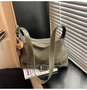 Detail of olive green tote bag featuring matte fabric panels and a leopard print charm