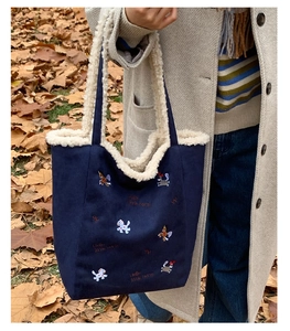 Dettaglio della borsa blu navy con manico in pile bianco e ricamo a forma di cavallo