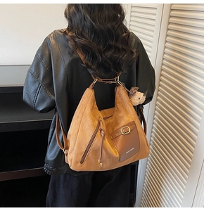 Close-up of brown suede tote bag with leather pocket and plush bear pendant detail