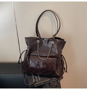 Detail of dark chocolate quilted tote with gold chain accent and glossy finish
