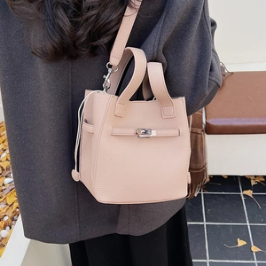 Close-up of litchi grain leather bucket bag with metal twist lock in autumn outdoor setting