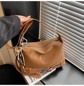 Detailed view of brown suede tote bag featuring decorative belt and leopard print pompom