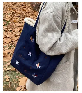Dettaglio borsa a secchiello blu navy con ricamo animale e interno in lana agnello