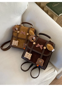 Close-up of vintage suede backpacks featuring cute cartoon patches and contrast leather trim