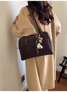Detail of dark brown tote bag with leopard fur ball and heart mirror charm on strap