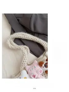 Detail of crochet tote bag with wide straps featuring cute cat and bear plush charms