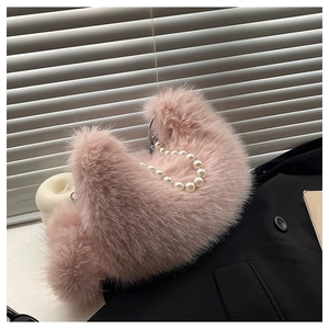 Détail d'un sac à main en fausse fourrure rose avec une anse élégante en perles nacrées