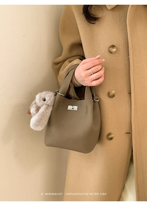 Close-up of olive green pebble leather bucket bag with metal lock and rabbit charm