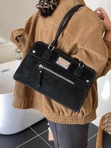 Retro matte black shoulder bag with metal logo and zipper pocket shown on a model
