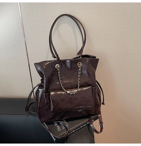 Close-up of quilted burgundy patent leather tote with metal chain and vintage texture