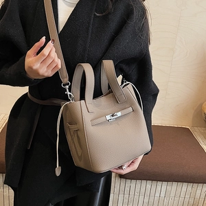 Litchi texture leather bucket bag shown on model with shoulder strap and top handles