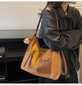 Detail of vintage brown suede tote bag with metallic buckle and dog charm on shoulder