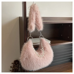 Détail du sac croissant en peluche rose avec chaîne de perles sur étagère bois