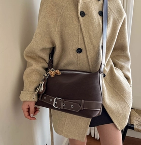 Detail of retro dark brown leather bag with a leopard print pompom and metal buckle