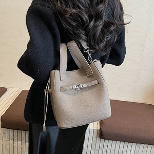 Taupe pebbled leather bucket bag worn by model with textured finish and crossbody strap