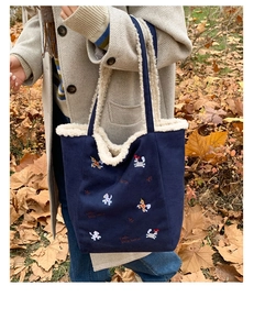 Dettaglio della borsa a secchiello in tela blu navy con bordo in peluche e ricamo