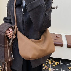 Brown textured leather crescent crossbody bag styled with a winter wool coat and scarf