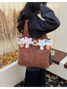 Detail of a brown knit tote bag with plush cat head charms and hollow woven texture