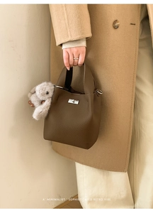 Detail of dark brown leather bucket bag with silver turn-lock and plush bunny charm
