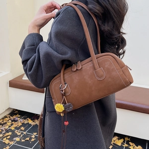 Dettaglio borsa in pelle vintage marrone con cuciture a contrasto e ciondolo decorativo