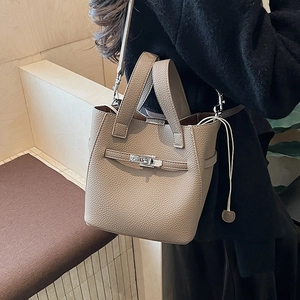 Close-up of litchi-grain taupe bucket bag showing metal twist lock and strap detail