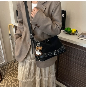 Detail of vintage black tote bag with moto-style buckle straps and leopard heart charm