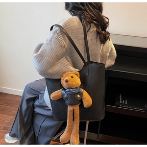 Detail der schwarzen Shopper-Tasche aus Kunstleder mit Teddybär-Anhänger und Trageriemen