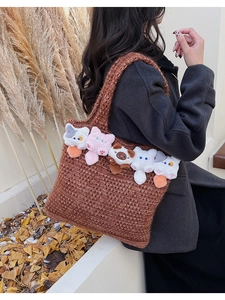 Detail of brown crochet tote bag with five cute plush cat dolls in warm autumn scenery