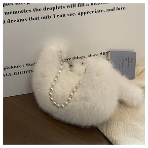 Détail du sac croissant en peluche blanche avec texture douce et chaîne de perles chic