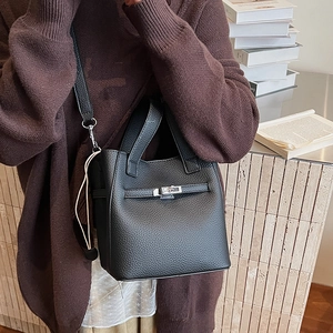 Detail of black lychee grain leather bucket bag with silver metal twist lock and strap