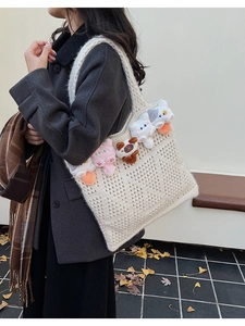Detail of cream knit tote bag featuring cute plush cat charms and textured crochet weave