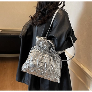 Detail of silver quilted drawstring bucket bag featuring a metallic finish and rhomboid texture