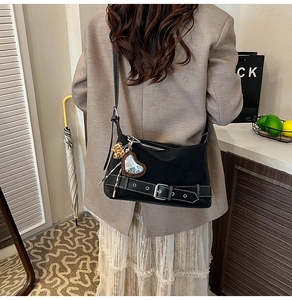 Close-up of black retro tote bag with metal buckle and leopard heart charms on a model