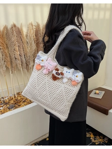 Detailed close-up of a beige knit tote bag featuring five colorful plush cat ornaments