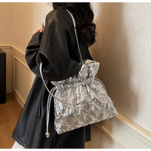 Detail of silver quilted puffer tote bag with drawstring closure and metallic finish surface