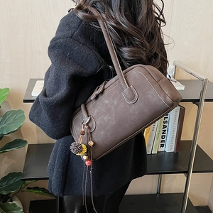 Dettaglio della borsa boston marrone scuro con cuciture a contrasto e nappa floreale