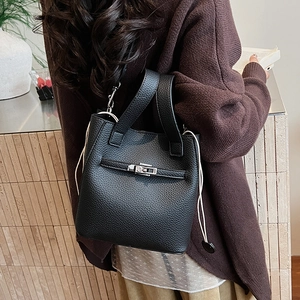 Detail of black lychee grain leather bucket bag with metal clasp and white drawstrings