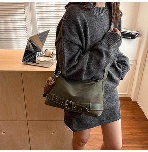 Detail of dark green vintage tote bag with metal buckle and leopard print plush pendant
