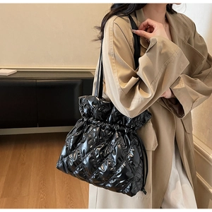 Detail of black glossy quilted shoulder bag with drawstring closure and chic lattice texture