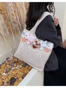 Detail of crochet tote bag featuring colorful knit kittens on beige openwork texture