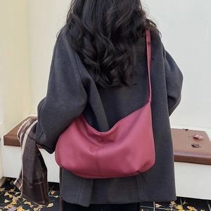 Close-up of deep red leather crescent bag texture with autumn leaf background