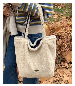 Dettaglio borsa tote in ecopelliccia crema con fodera blu e logo ovale in metallo