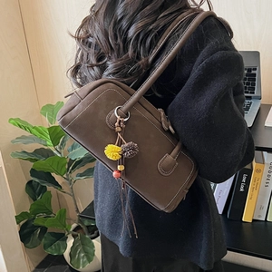 Borsa bowling in pelle marrone con cuciture bianche e ciondolo a pompon colorato