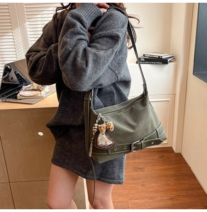 Detail view of dark green hobo bag with buckled straps and heart leopard charm