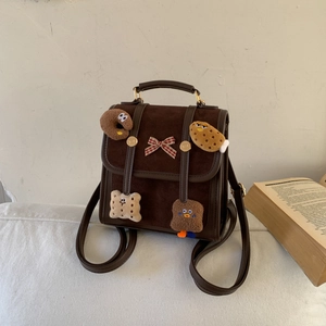 Detail of vintage brown mini backpack with cute plush cartoon charms and bow decoration