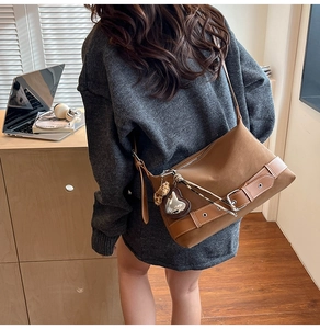 Brown leather tote bag featuring heart mirror charm and leopard pompom on model
