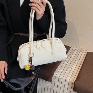 Dettaglio della borsa bowling in pelle martellata crema con doppia zip e ciondolo pompon