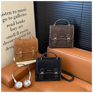 Three retro suede-textured handbags in brown, coffee, and black on a sofa